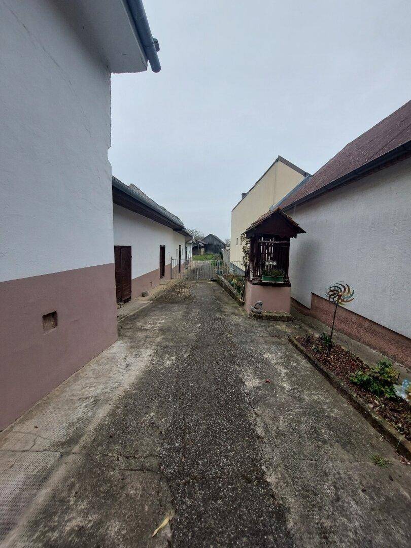 Schmaler Betonweg zwischen den Gebäuden, der zum hinteren Bereich des Grundstücks führt.