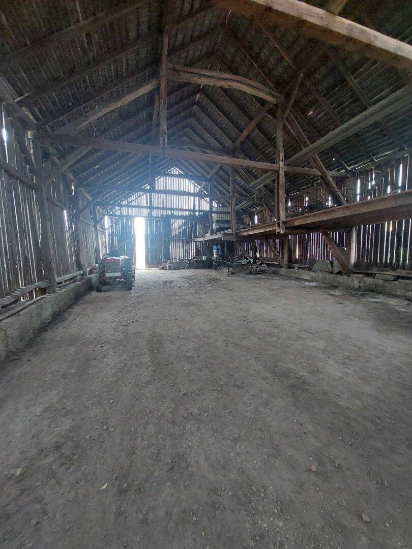 Weitläufige Scheune mit hoher Decke und offener Holzkonstruktion, viel Platz für Lagerung.