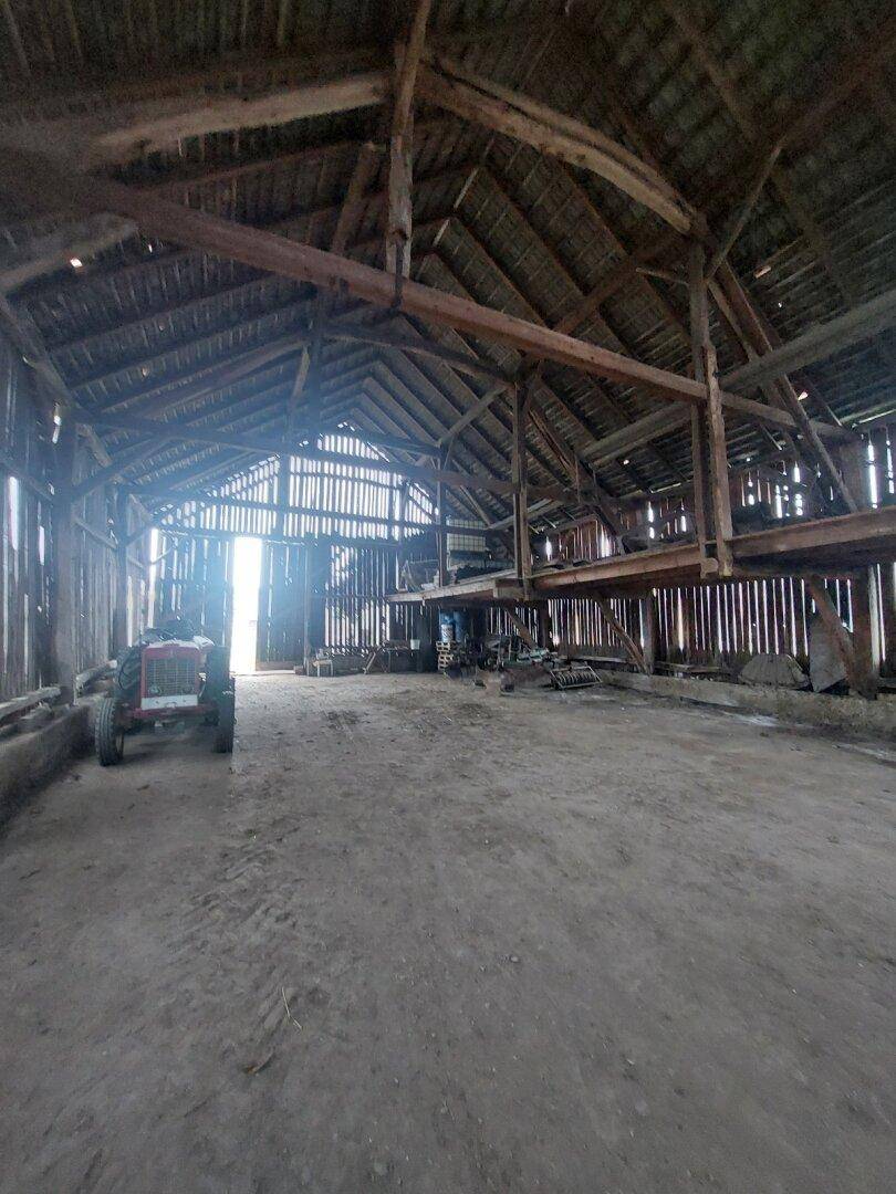 Geräumige Scheune mit hoher Holzkonstruktion, freiliegenden Balken und natürlichem Lichteinfall.