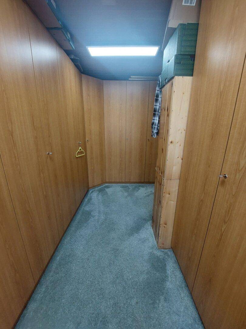 Praktischer Abstellraum mit Einbauschränken aus Holz und Teppichboden.