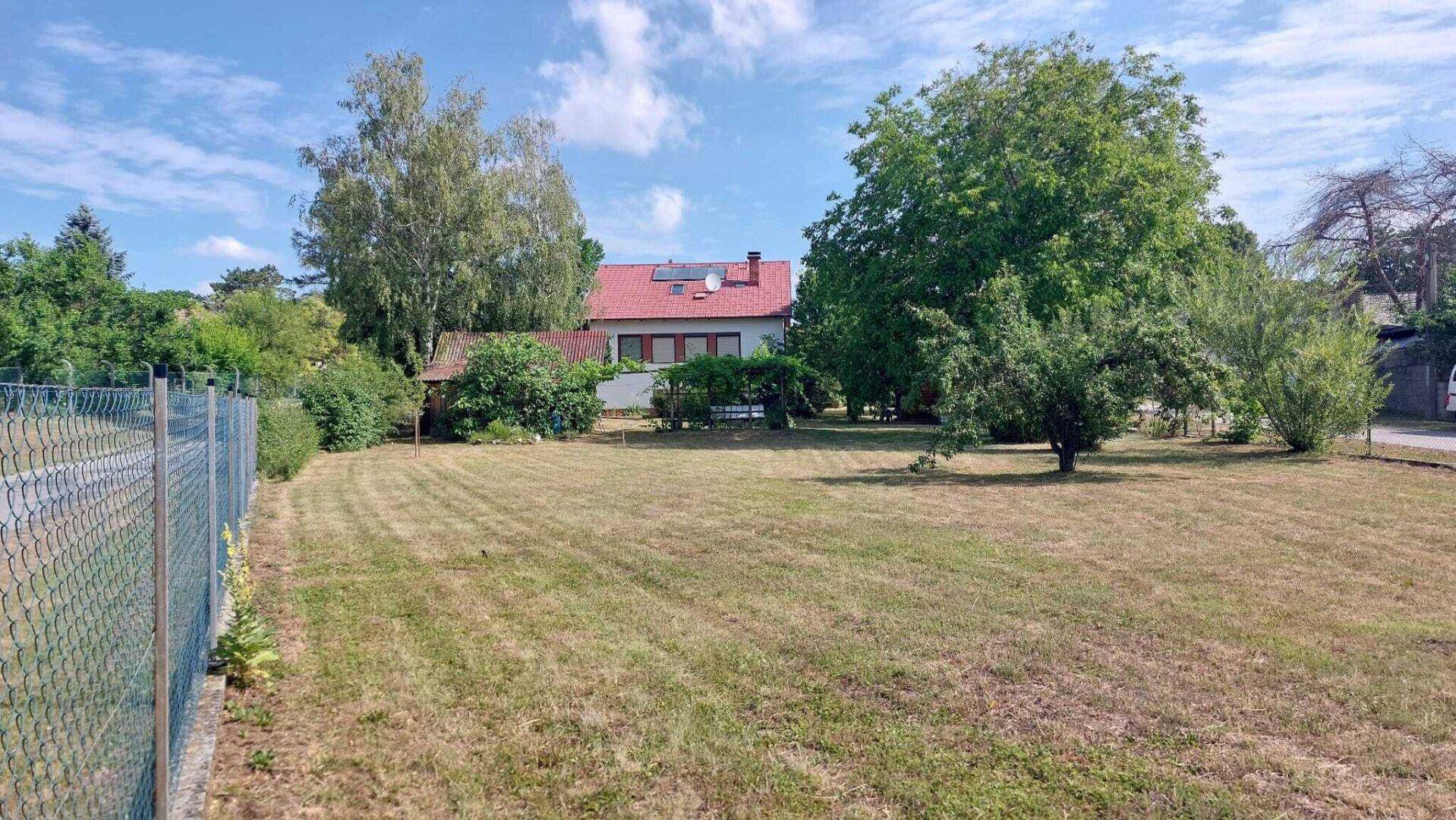Weitläufige Rasenfläche des Gartens mit Blick auf das Wohnhaus im Hintergrund.