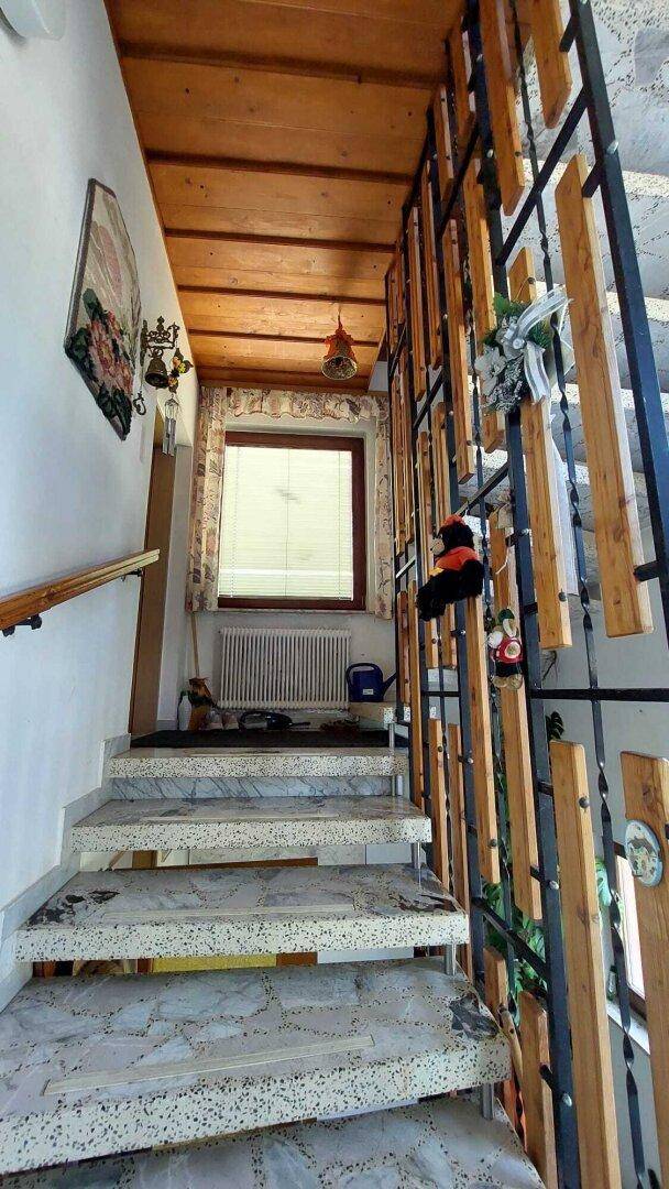 Treppenhaus mit Marmorstufen, Holzdecke und einem Fenster für natürliches Licht.