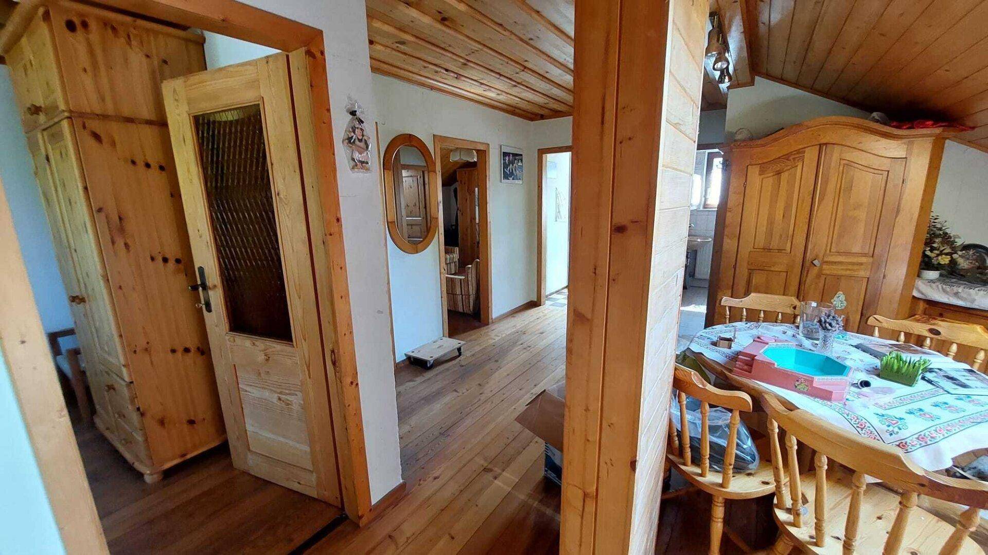 Dachgeschossbereich mit Holztüren, Holzmöbeln und schräger Holzdecke.
