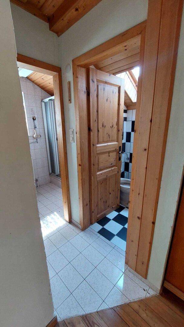 Flur im Dachgeschoss mit Fliesenboden, Holztüren und Zugang zu Bad und WC.