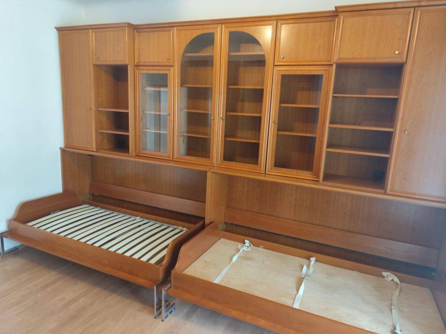 Schlafzimmer mit zwei Einzelbetten und integrierten Holzschränken.