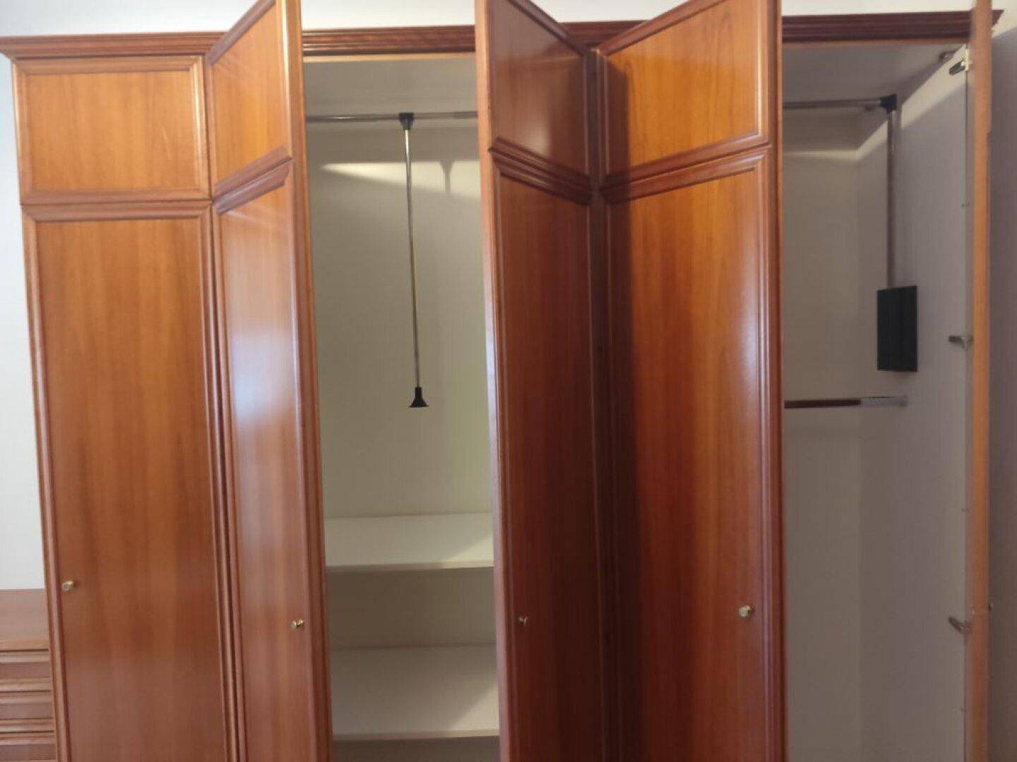 Geräumiger Kleiderschrank aus Holz mit mehreren Fächern und Kleiderstangen.