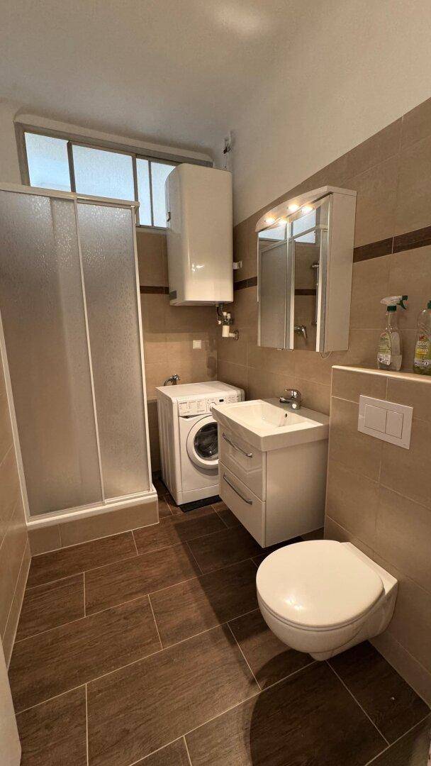 Modernes Badezimmer mit Dusche, WC, Waschbecken und Waschmaschine.