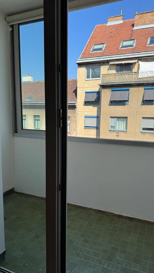 Verglaster Balkon mit Blick auf die umliegenden Gebäude und den blauen Himmel.