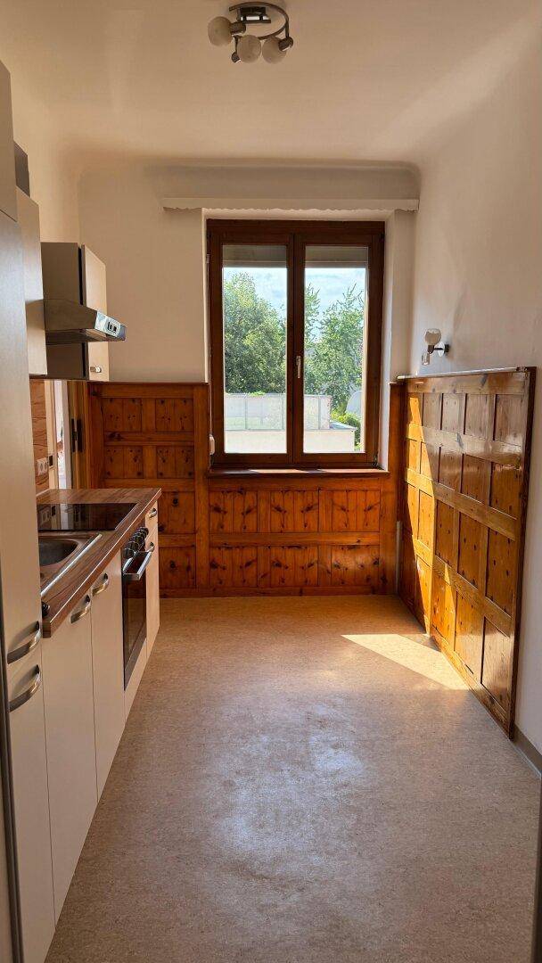Helle Küche mit Fenster und Holzvertäfelung, bereit für die Installation einer Einbauküche.