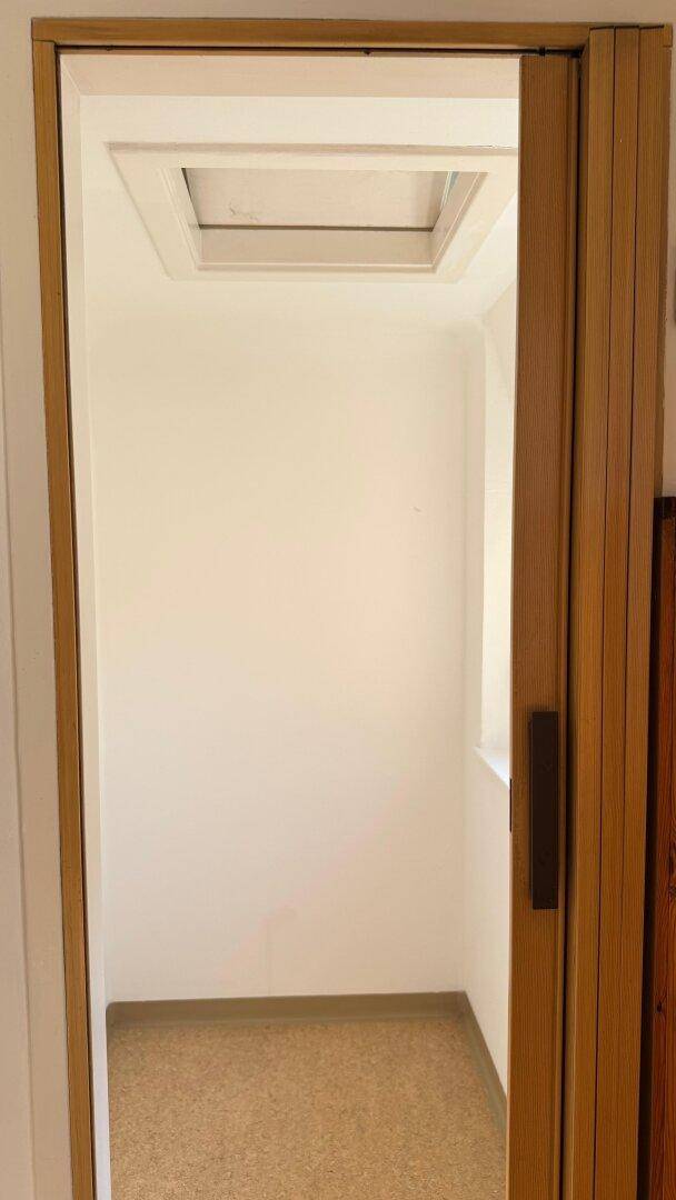 Kleiner Raum mit Dachfenster und hellem Boden, ideal als Abstellraum.