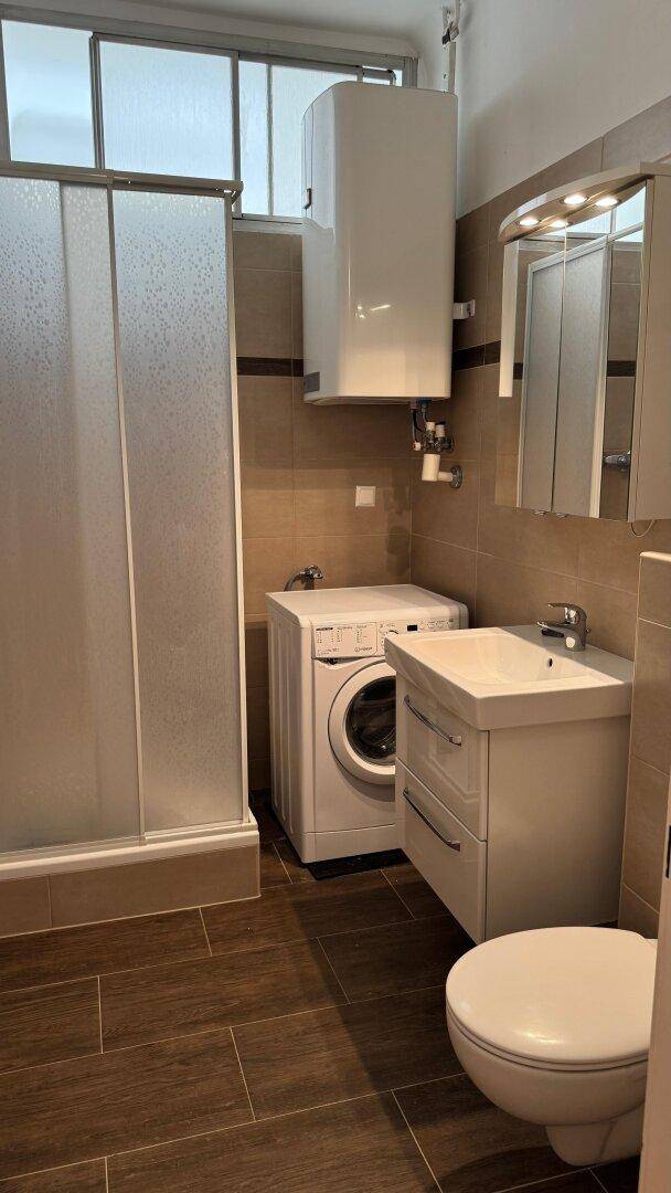 Modernes Badezimmer mit Dusche, WC, Waschbecken und Waschmaschine.