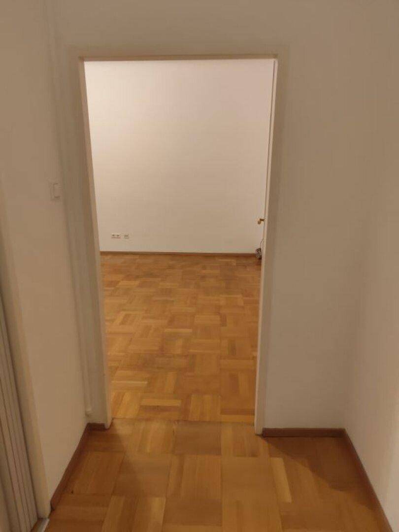 Heller Flur mit Parkettboden, der zu einem weiteren Raum führt.