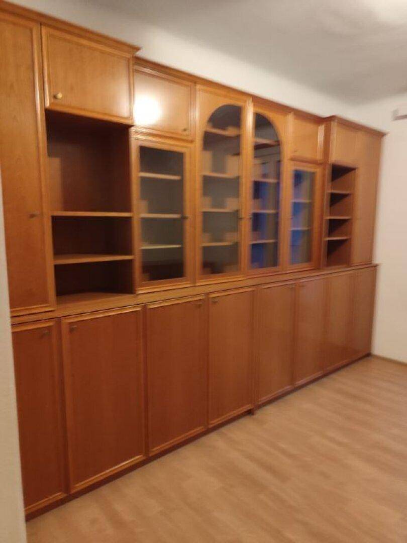 Großer Holzschrank mit Vitrinen und Regalen in einem hellen Raum mit Laminatboden.