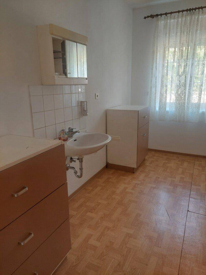 Kleiner Raum mit Waschbecken, Schränken und Fenster.