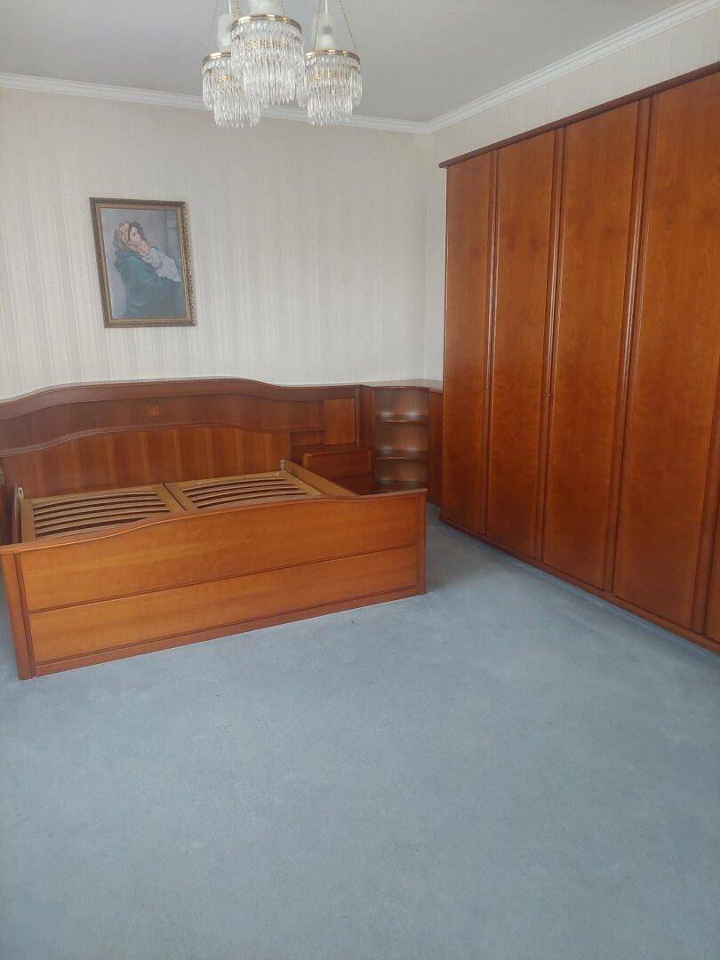 Schlafzimmer mit Teppichboden, Holzmöbeln und Kronleuchter.