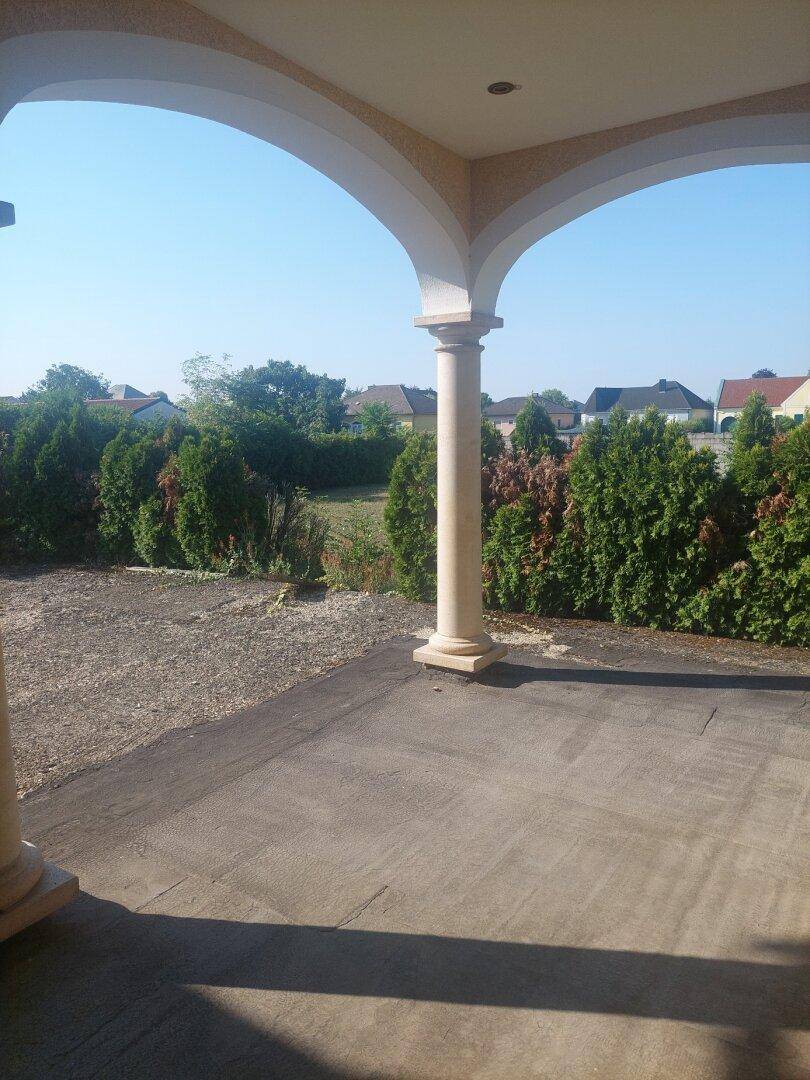 Überdachte Terrasse mit Säulen und weitem Blick ins Grüne.