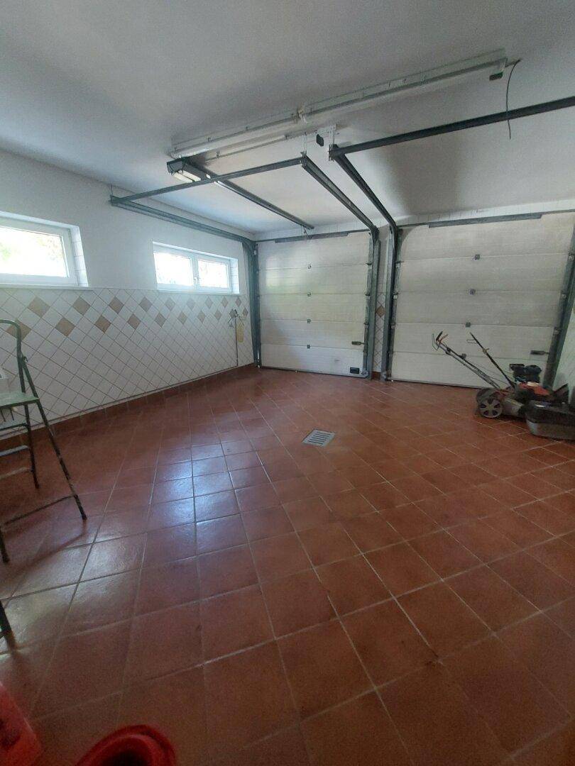Geräumige Doppelgarage mit Fliesenboden und zwei Rolltoren.
