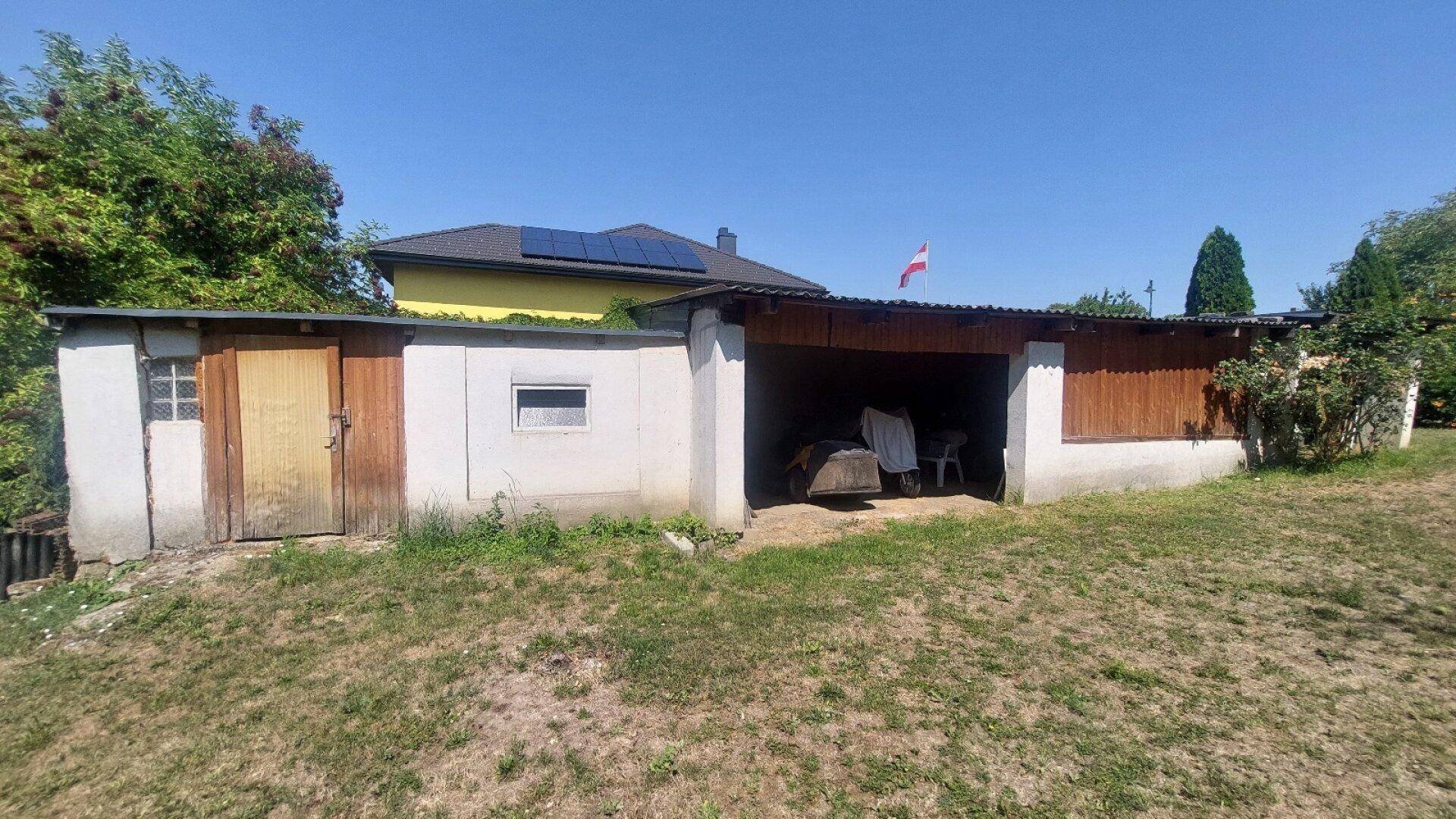 Einfache Garage und Nebengebäude mit Holztüren und einem Carport-Bereich.