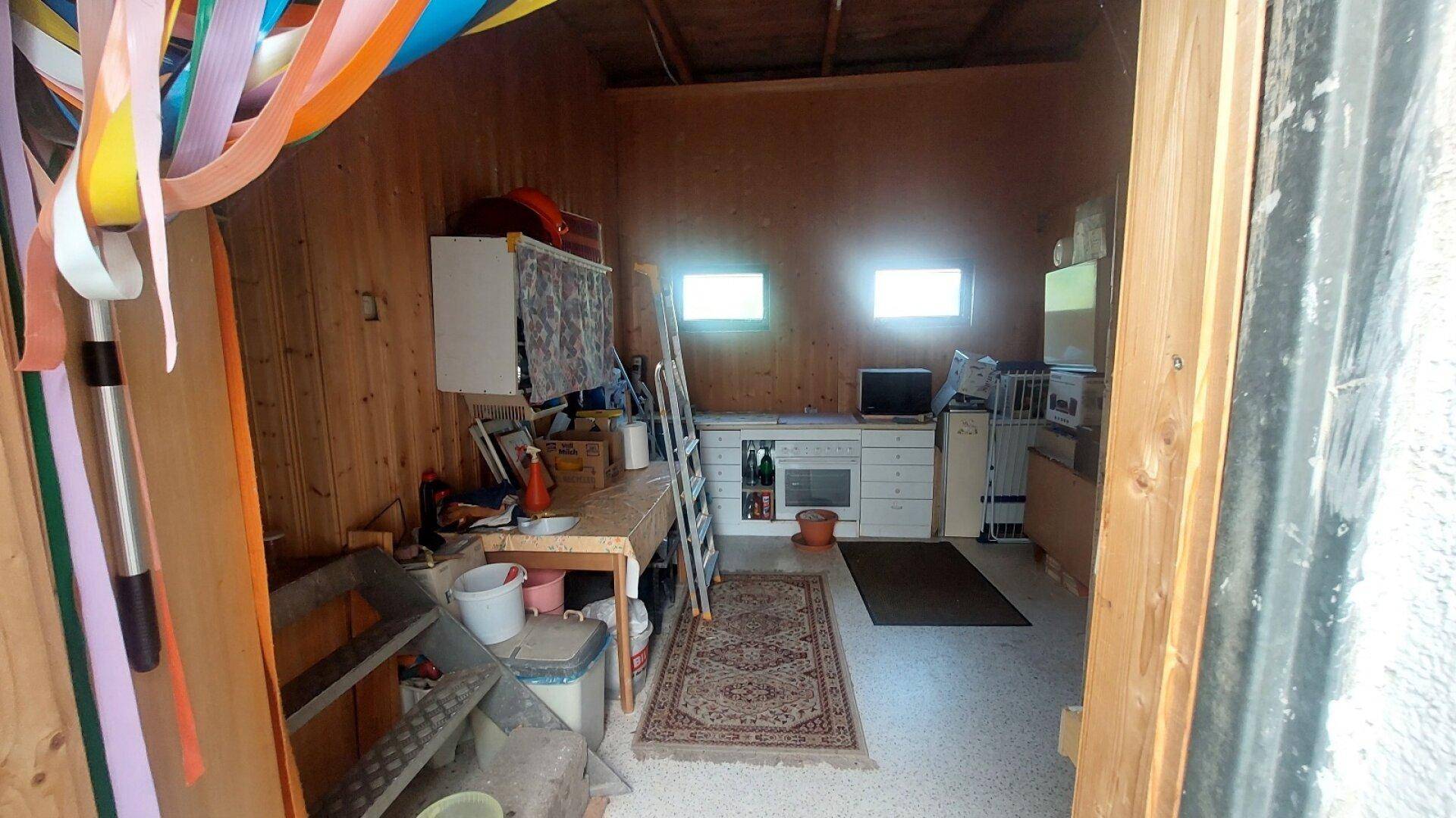 Rustikaler Abstellraum oder Werkstatt mit Holzvertäfelung und kleiner Küchenzeile.