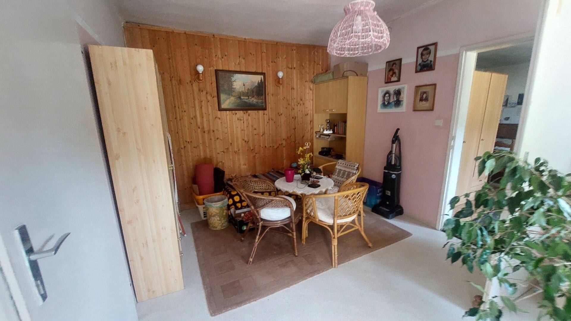Gemütlicher Essbereich mit Holzvertäfelung, Korbmöbeln und rosa Wandakzenten.
