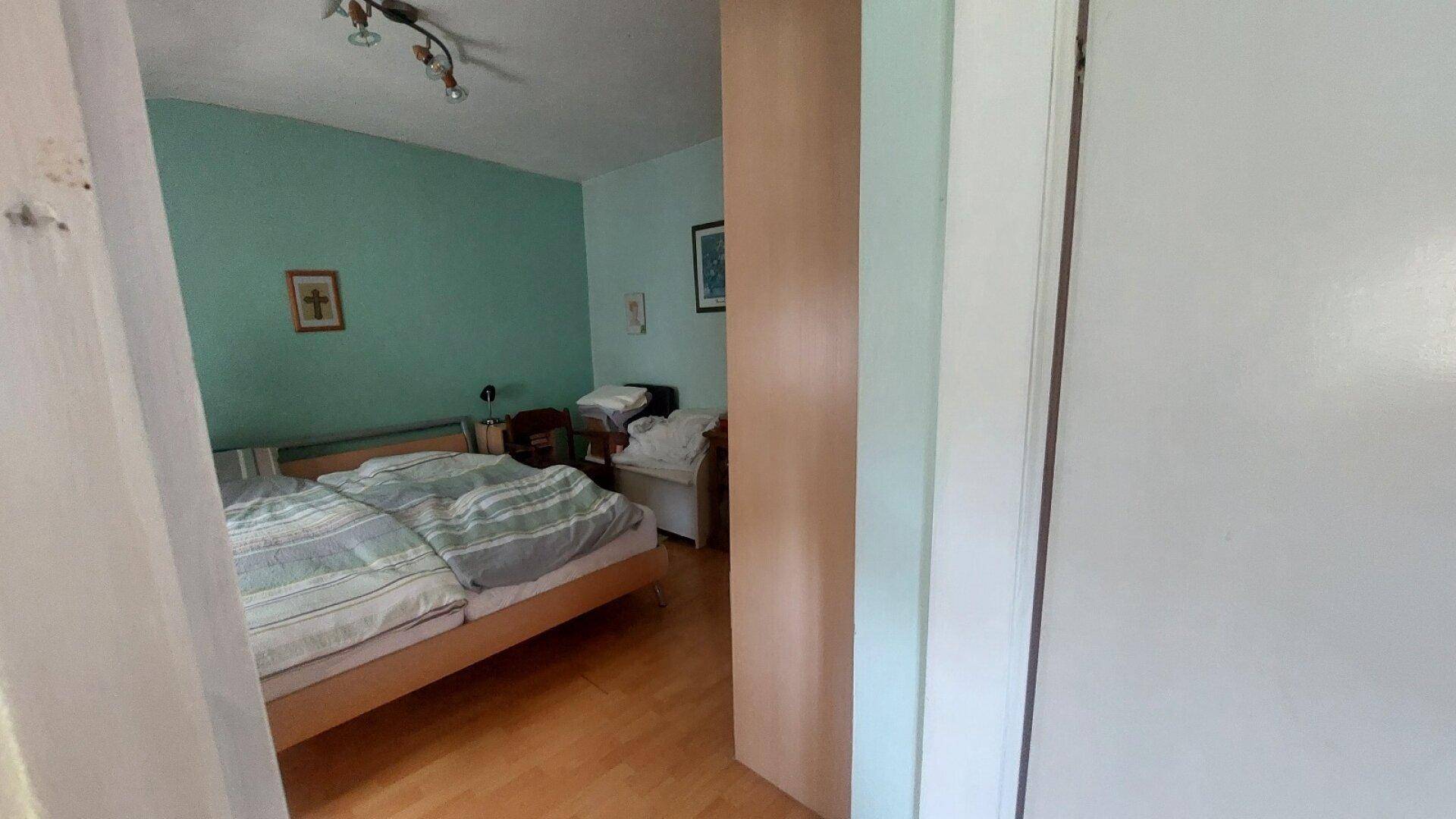 Schlafzimmer mit Holzboden, Doppelbett und hellblauen Wänden.