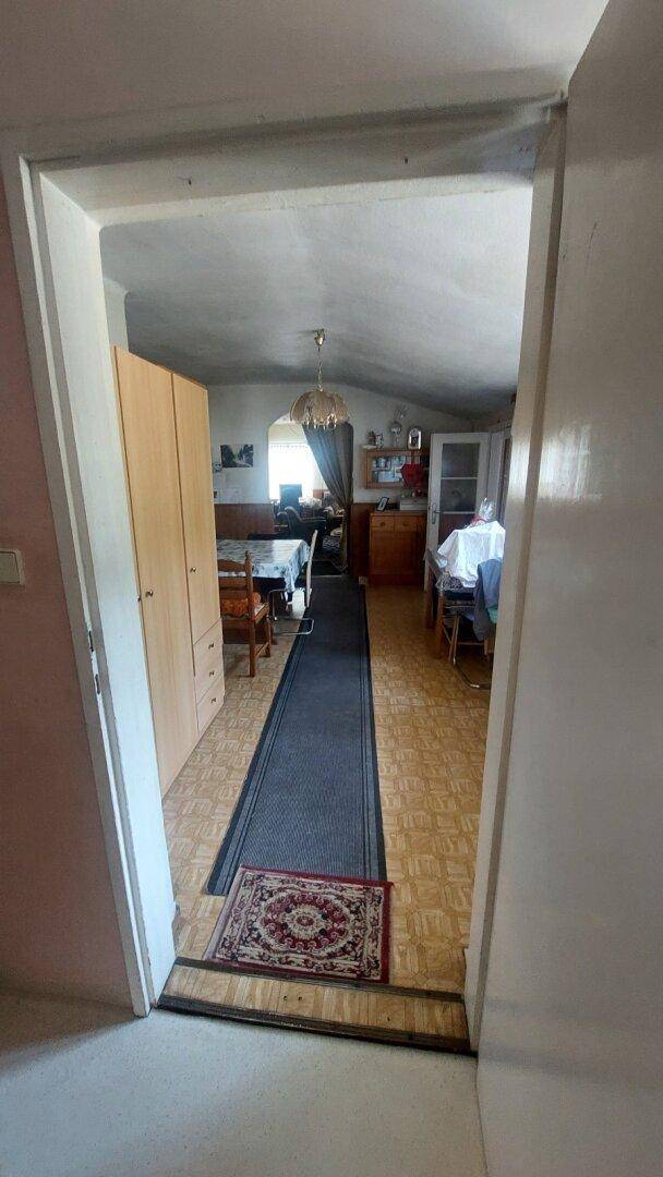 Langer Flur mit Teppichläufer, der zu einem Essbereich und weiteren Räumen führt.