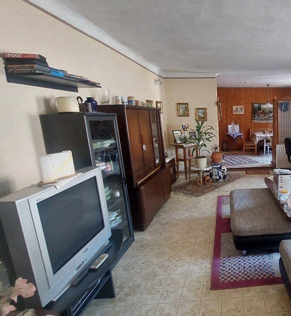 Geräumiges Wohnzimmer mit Fliesenboden, traditionellen Möbeln und Blick in den Essbereich.
