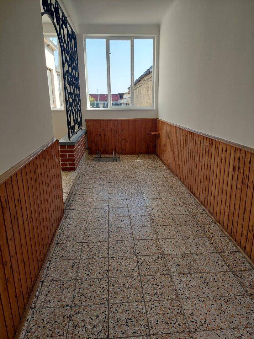 Heller Flur mit Terrazzoboden und Holzvertäfelung, der zu weiteren Räumen führt.