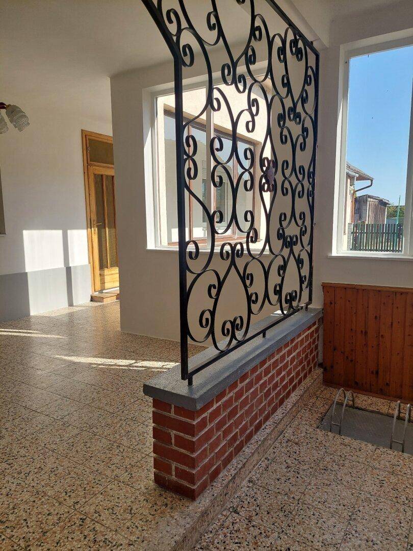 Detailansicht des Flurs mit dekorativem schmiedeeisernem Geländer und Terrazzoboden.