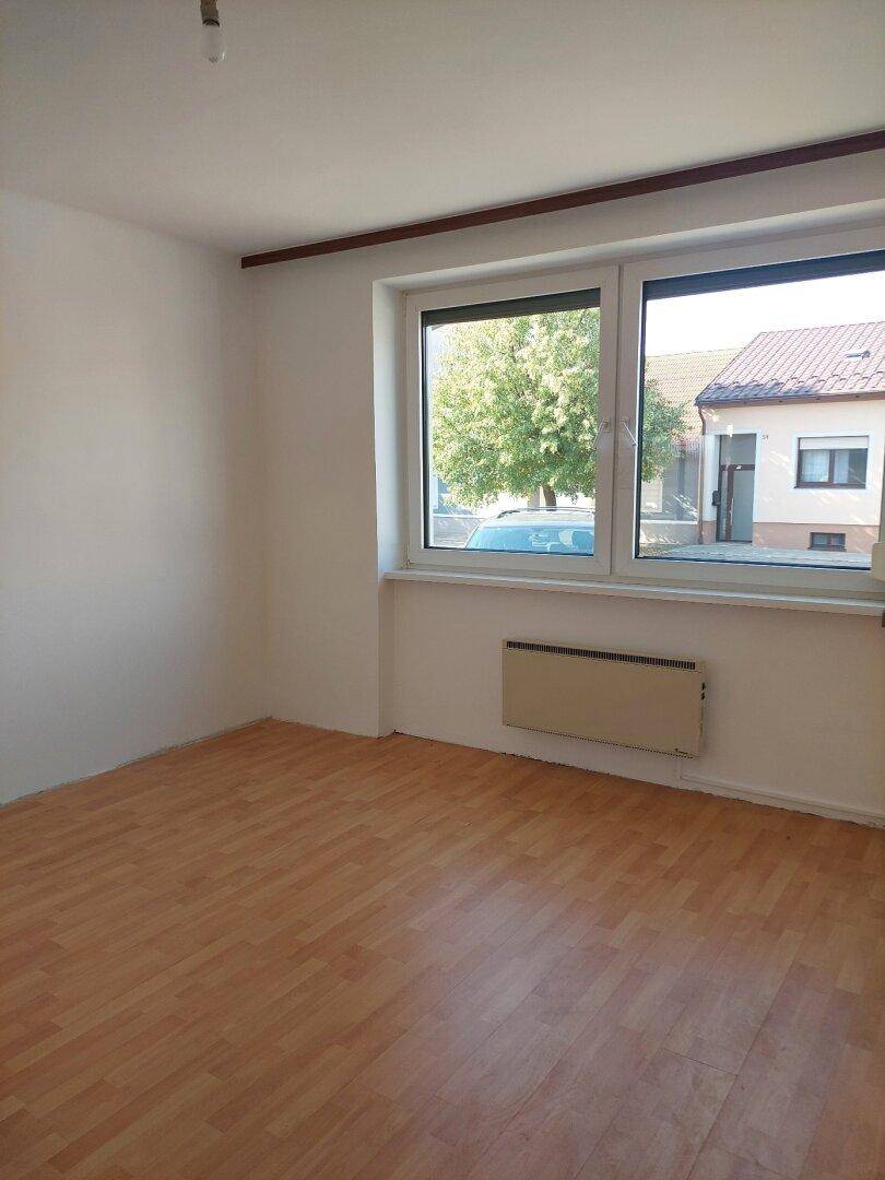Helles Zimmer mit Laminatboden und Fensterblick ins Grüne, ausgestattet mit Heizkörper.