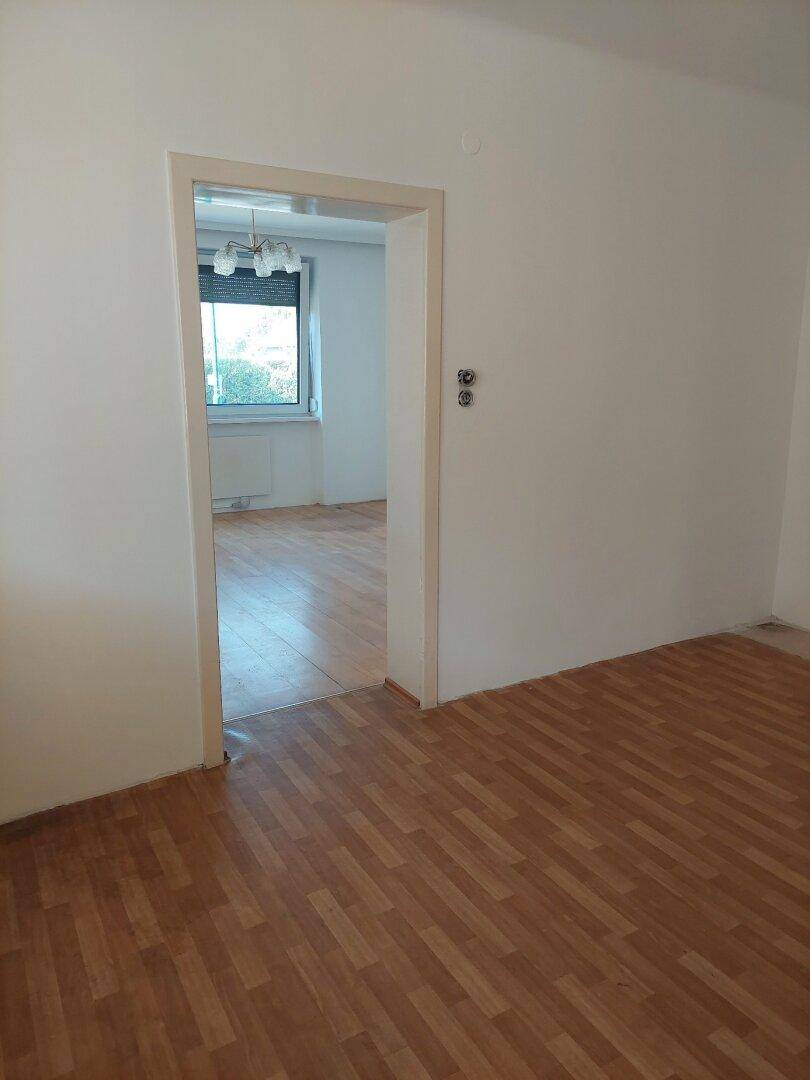 Durchgang zwischen zwei hellen Zimmern mit Parkettboden, ideal für offenes Wohnen.