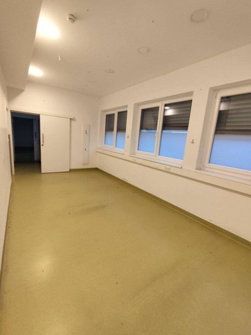 Heller Büroraum mit großen Fenstern und Schiebetür, bietet viel Tageslicht und Flexibilität.