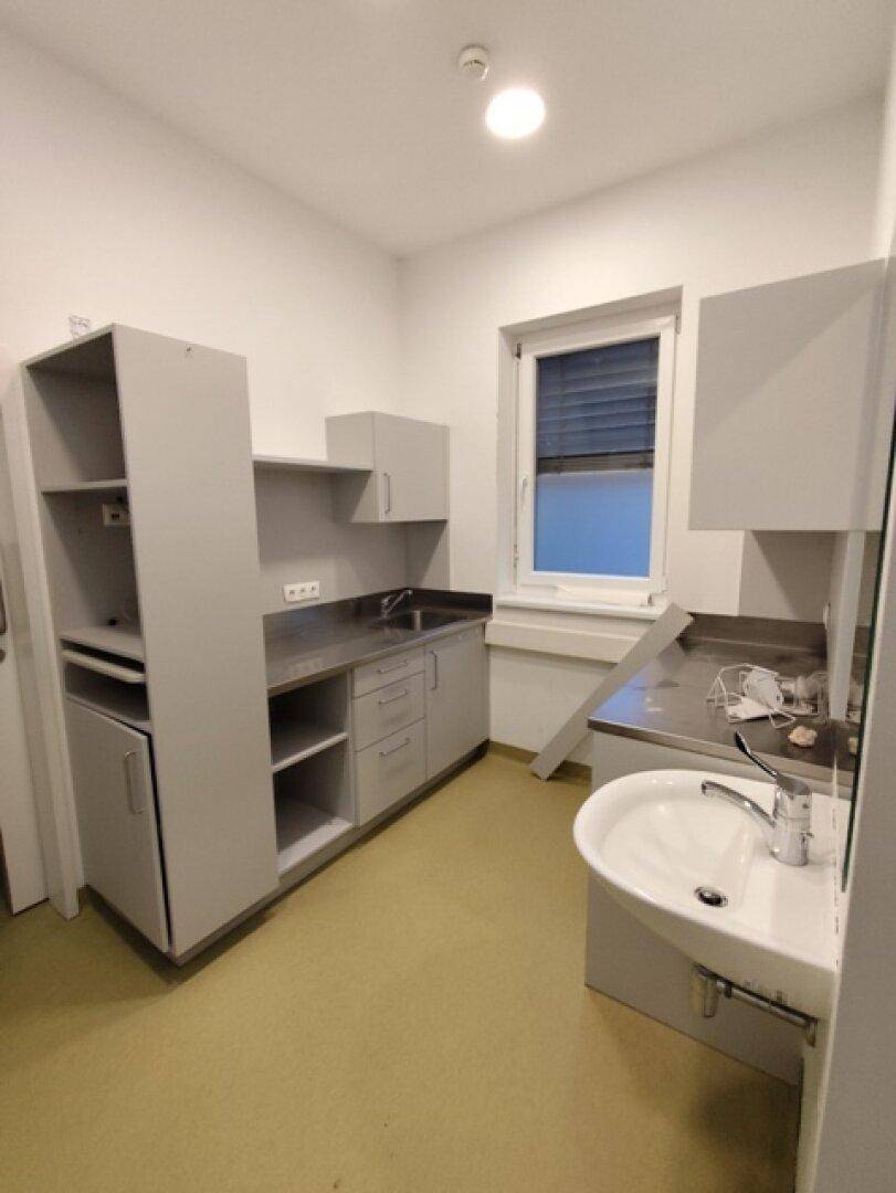 Funktionale Küchenzeile mit Spüle, Schränken und Arbeitsflächen, ergänzt durch ein Waschbecken.