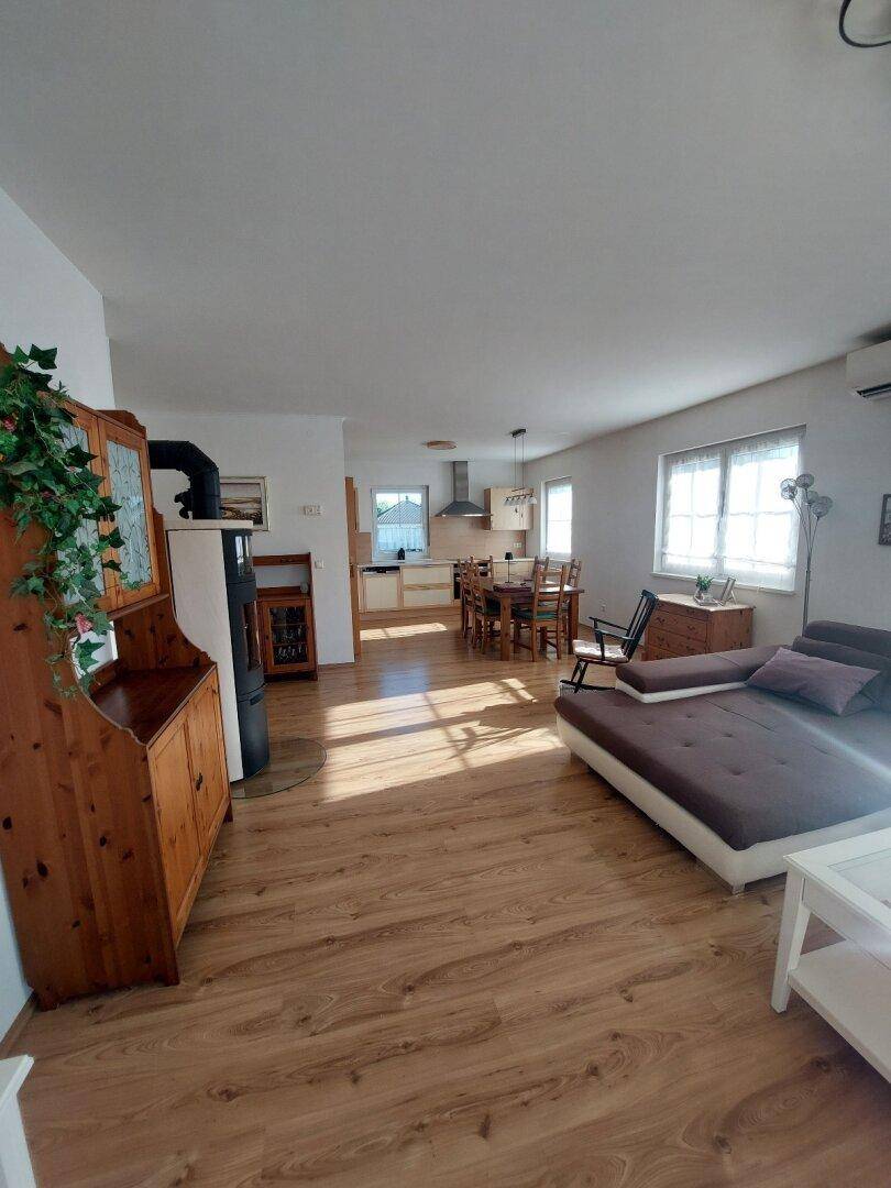Geräumiger Wohnbereich mit Kaminofen, Laminatboden und Blick auf die offene Küche.