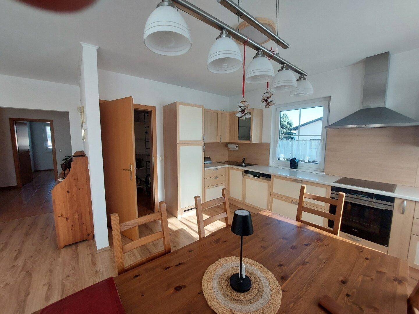 Helle Einbauküche mit Holzelementen, Esstisch und modernen Geräten.