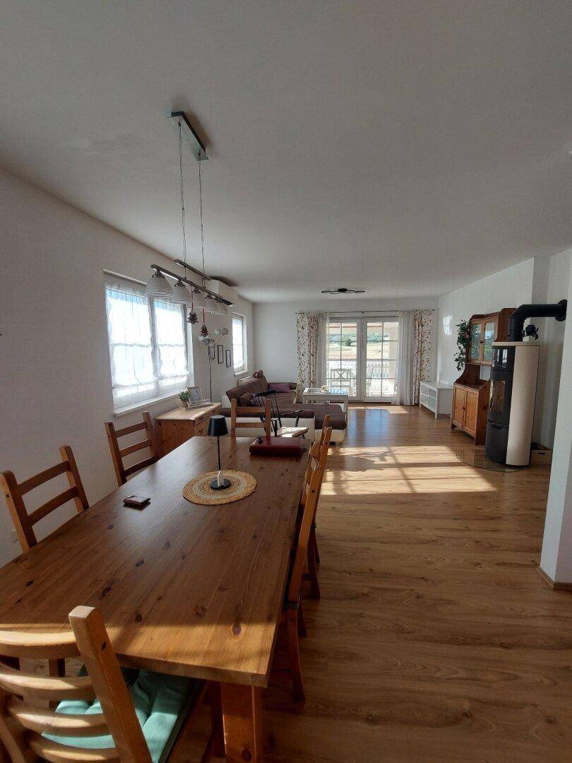 Lichtdurchfluteter Wohn- und Essbereich mit Holztisch, Laminatboden und Zugang zur Terrasse.