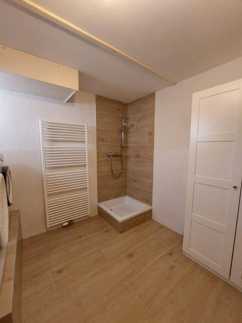 Duschbereich im Hauswirtschaftsraum mit modernen Fliesen und Handtuchheizkörper.