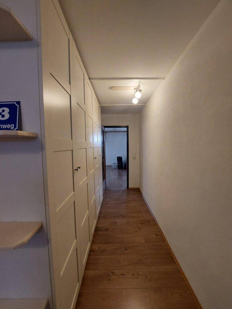 Langer Flur mit Einbauschränken und Holzboden, der zu weiteren Räumen führt.