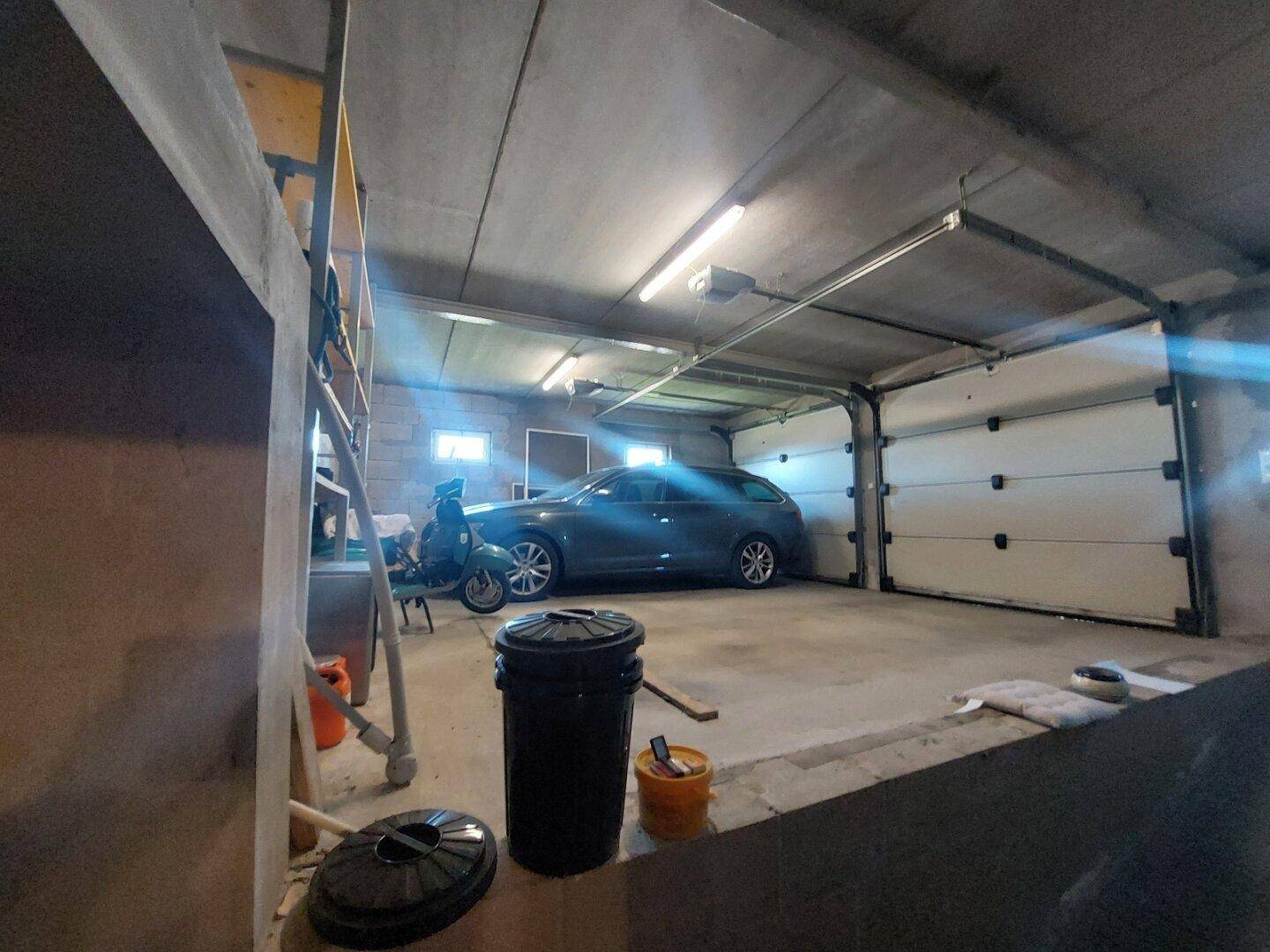 Geräumige Garage mit Platz für ein Auto und Motorroller, ausgestattet mit Rolltoren.