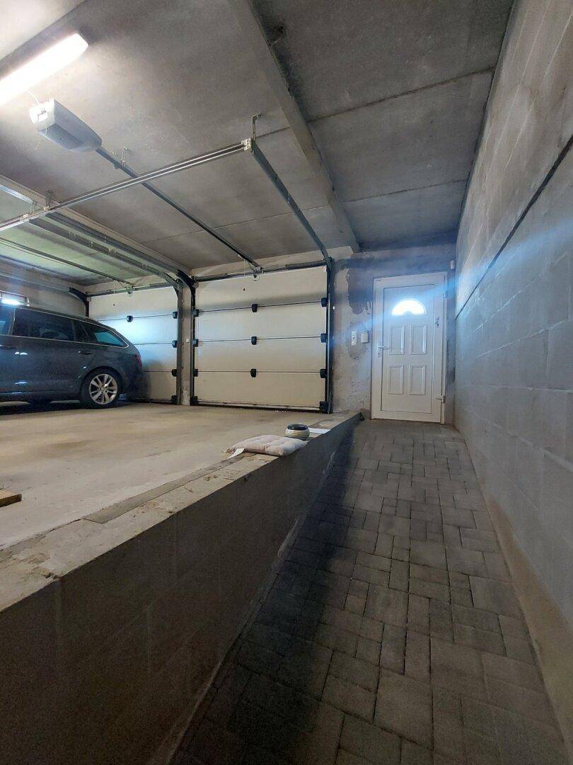 Eingangsbereich zur Garage mit Rampe und zwei großen Garagentoren.