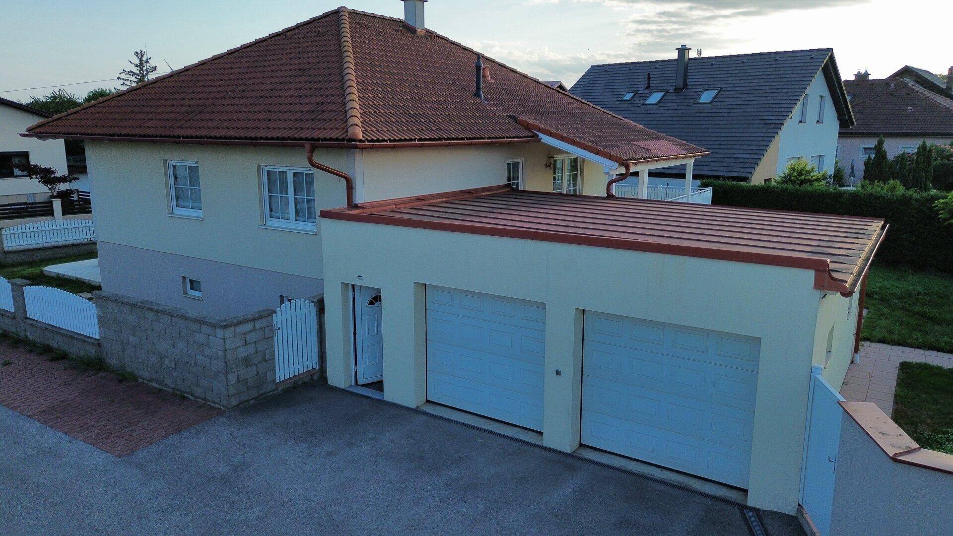Ansicht des Hauses von hinten mit Doppelgarage und rotem Ziegeldach.