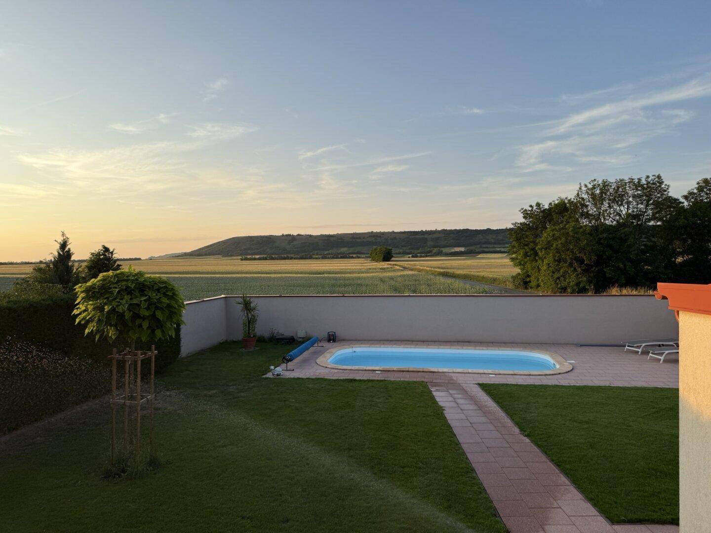 Großer Garten mit Swimmingpool, Rasenfläche und weitem Blick auf die Landschaft.