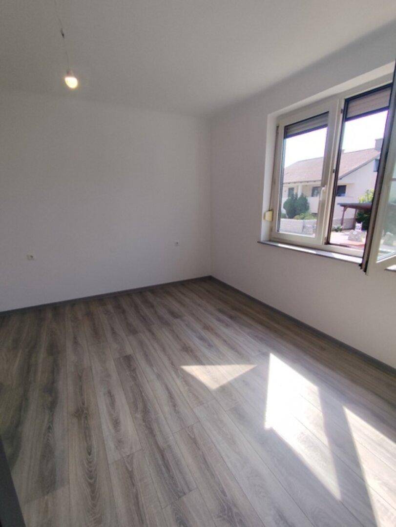 Geräumiger Raum mit Laminatboden und Fenster, das einen Blick nach draußen ermöglicht.