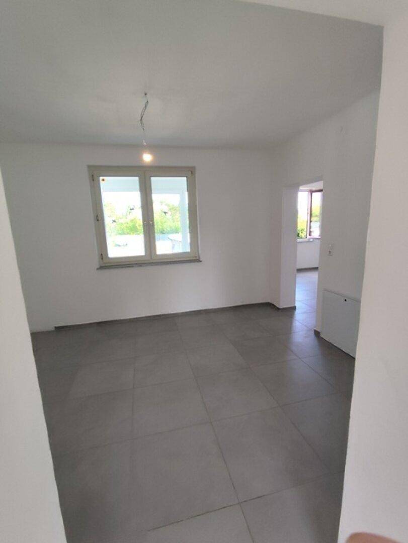Leerer Raum mit Fliesenboden und Fenster, das viel Tageslicht hereinlässt.