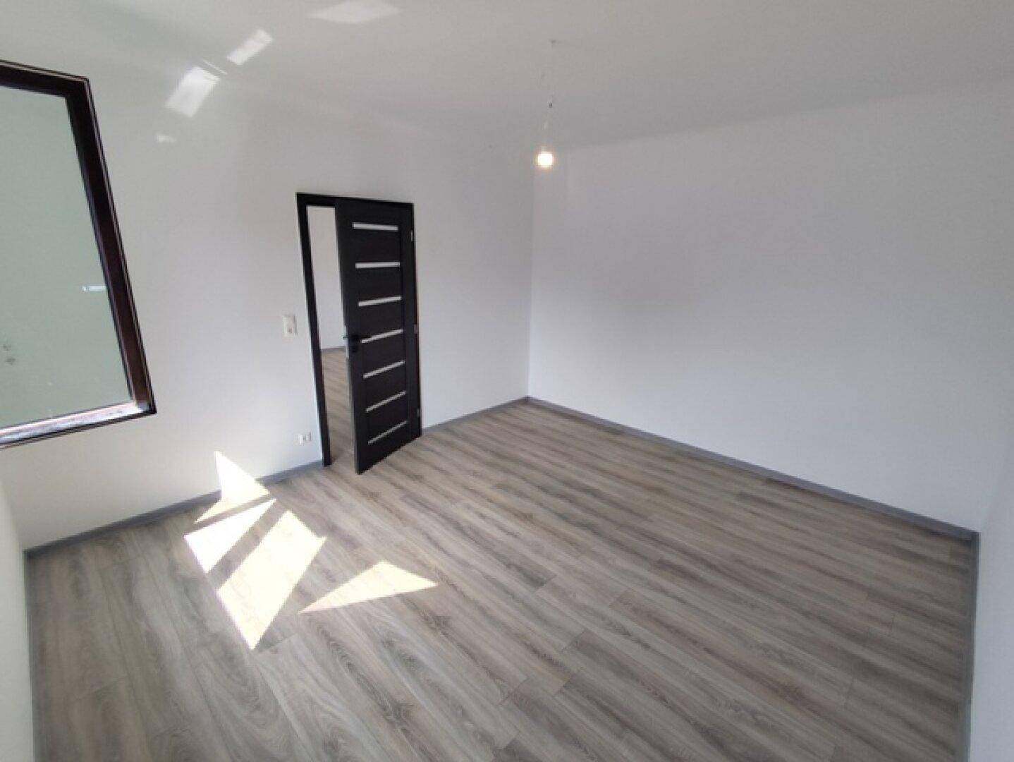 Heller Raum mit Laminatboden und großem Fenster, das viel Tageslicht bietet.