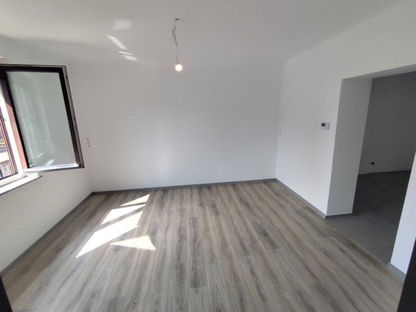 Geräumiger Raum mit Laminatboden und Fenster, das den Blick nach draußen freigibt.