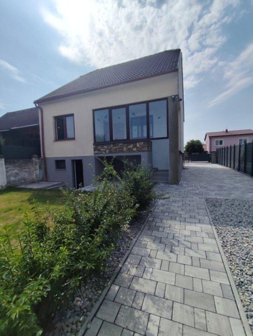 Seitenansicht des Hauses mit gepflasterter Zufahrt und einem kleinen Gartenbereich.