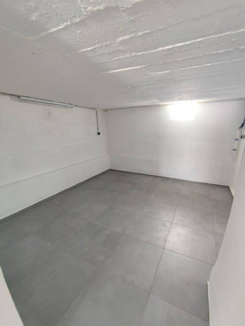 Heller Kellerraum mit Fliesenboden und einem kleinen Fenster, das Tageslicht spendet.