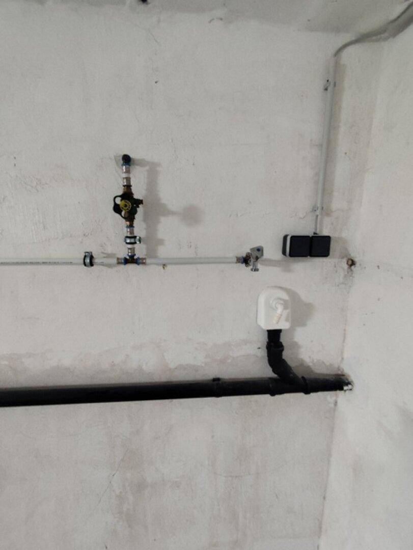 Nahaufnahme von Wasserleitungen und Ventilen an einer Wand im Hauswirtschaftsraum.