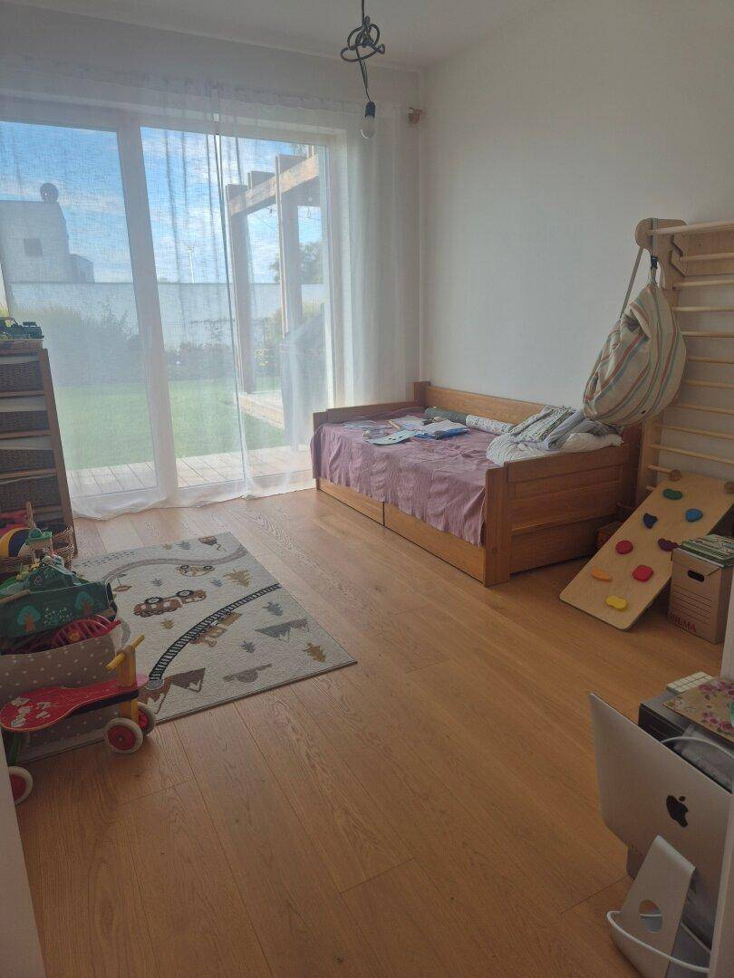 Kinderzimmer mit Holzboden, viel Tageslicht und Zugang zum Garten.